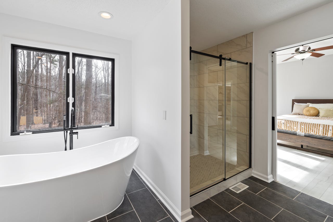 Sleek bathroom featuring a freestanding tub, glass shower, and a view of the forest.